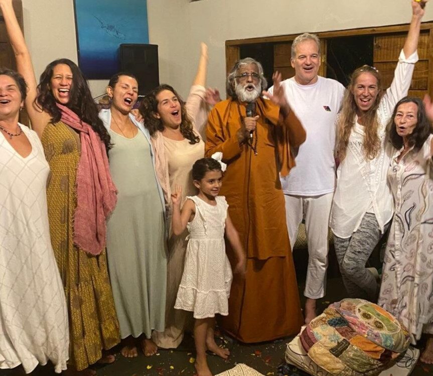 Guru AtmaNambi smiling during the Mass Awakening Brazil spiritual journey, surrounded by devotees at a satsang.