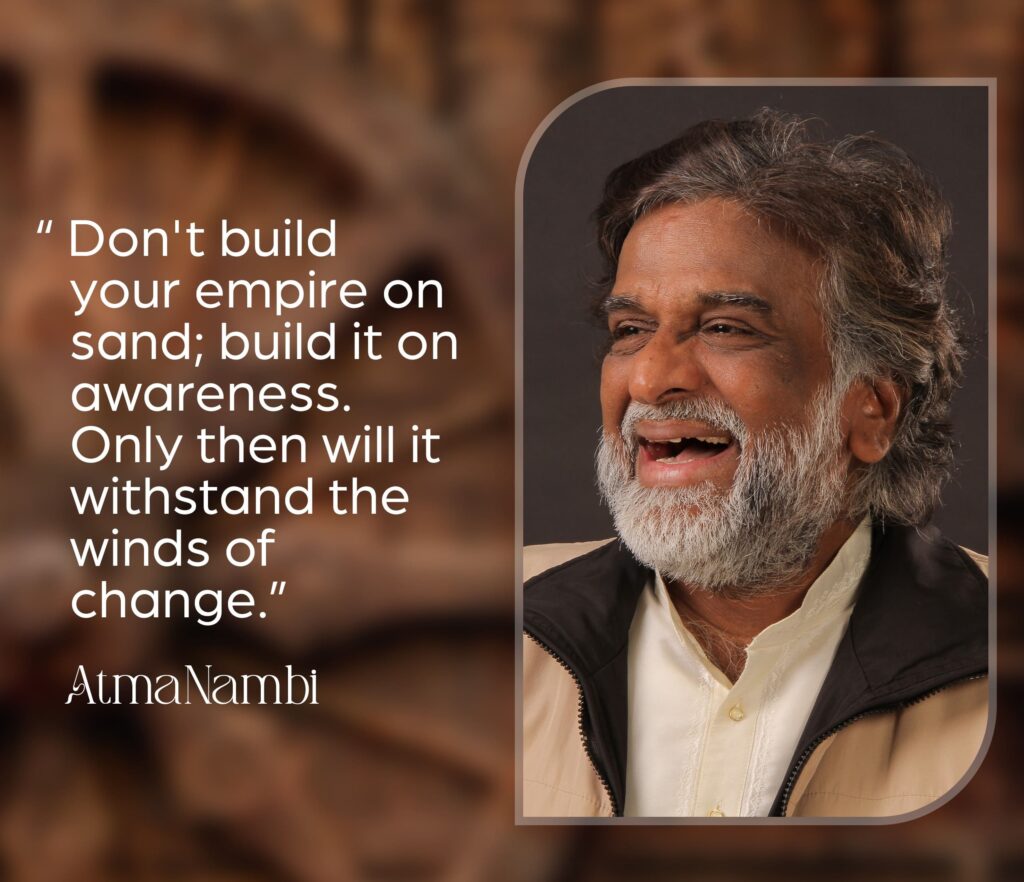 AtmaNambi spiritual quote poster urging seekers to build their empire on awareness rather than sand so it withstands the winds of change, featuring AtmaNambi smiling with joyful presence.