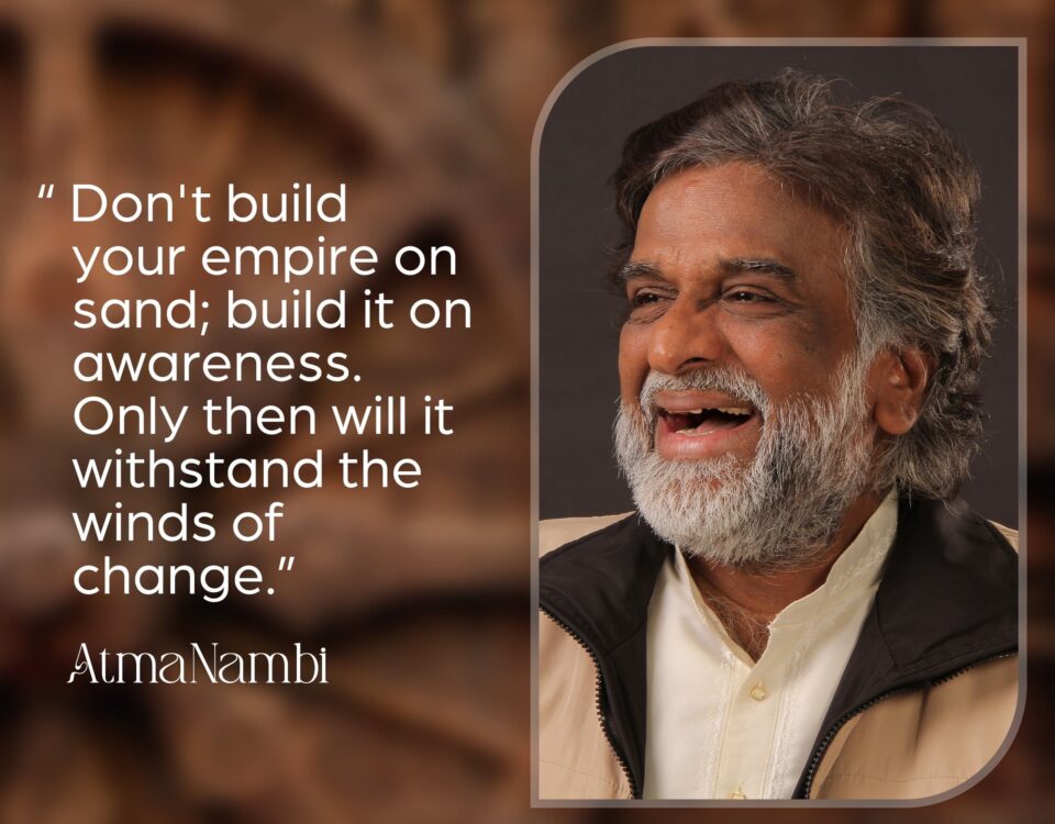 AtmaNambi spiritual quote poster urging seekers to build their empire on awareness rather than sand so it withstands the winds of change, featuring AtmaNambi smiling with joyful presence.