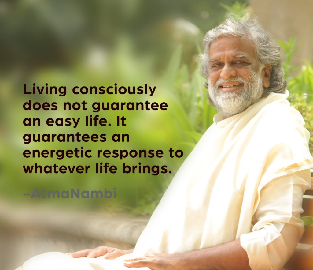 AtmaNambi spiritual quote poster showing the enlightened Indian master in white robes seated peacefully outdoors amid greenery, sharing his teaching that living consciously guarantees an energetic response to whatever life brings rather than an easy life.