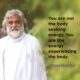 AtmaNambi, Indian enlightened master in white robes, with the spiritual quote "You are not the body seeking energy. You are the energy experiencing the body" — a pure energy spiritual awakening teaching.