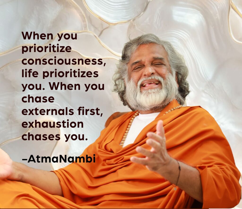 AtmaNambi, Indian enlightened master in saffron robes laughing joyfully with an open gesture, sharing his prioritize consciousness spiritual teaching that when awareness comes first, life flows and exhaustion falls away.