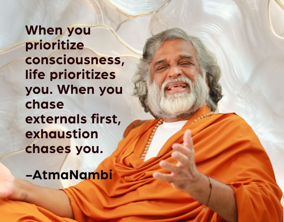 AtmaNambi, Indian enlightened master in saffron robes laughing joyfully with an open gesture, sharing his prioritize consciousness spiritual teaching that when awareness comes first, life flows and exhaustion falls away.